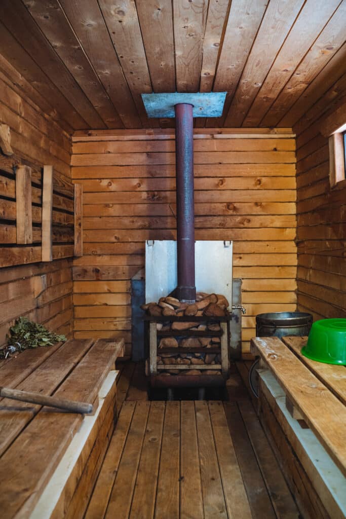 A charming wooden sauna featuring a traditional stove, along with a beautifully crafted green bowl, perfect for enhancing the relaxing atmosphere inside the sauna experience